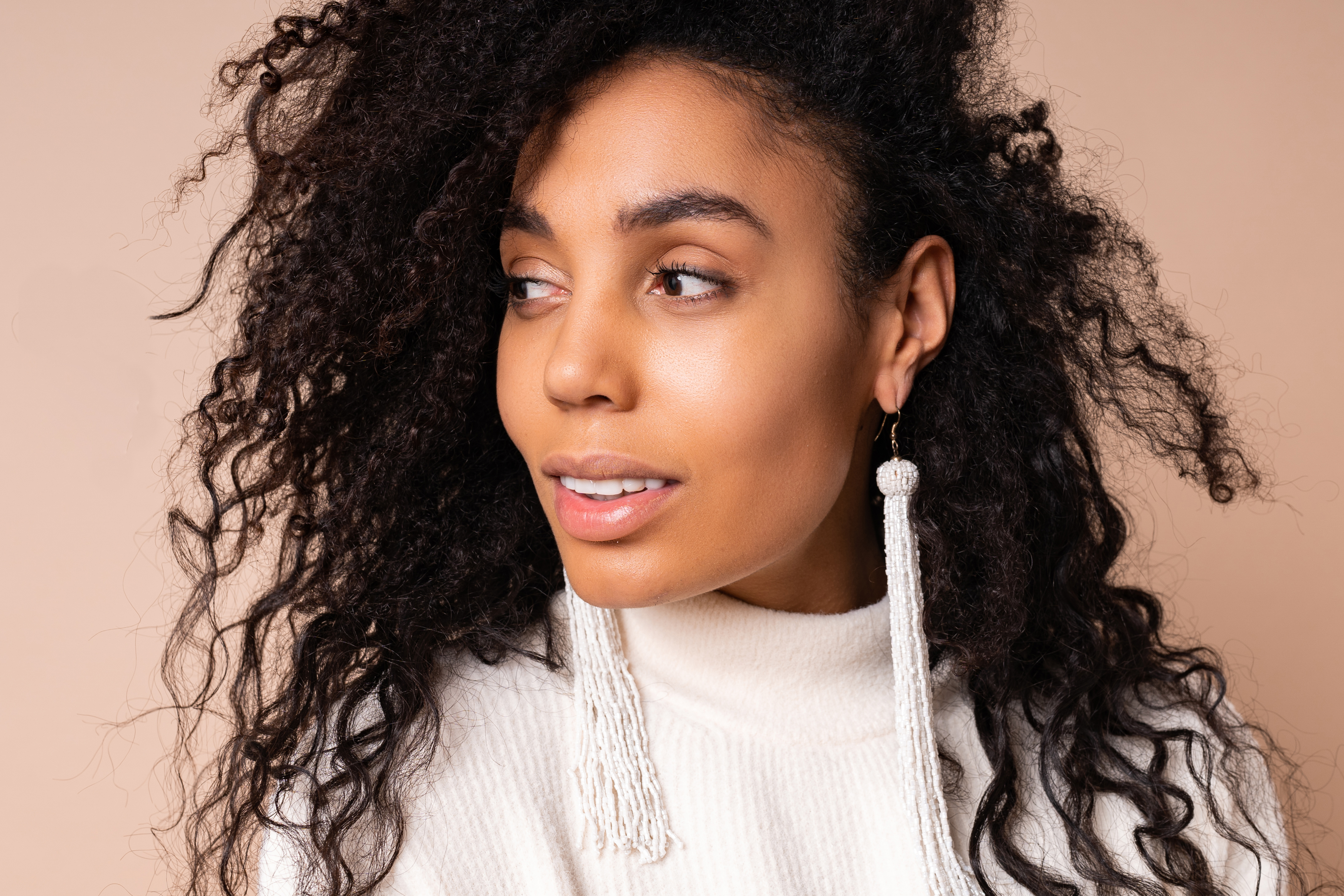 Woman with softly textured curls on a beige backdrop